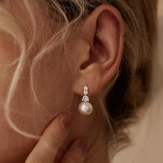 Pearl drop earring with three vertically stacked cubic zirconia stones worn on an ear